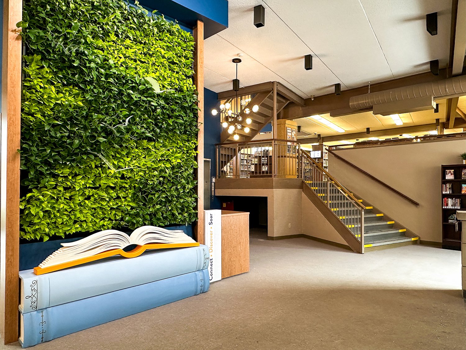 A wall of plants inside a front foyer with artwork birds in front of it. The Living Wall at the Orangeville Public Library's Mill Street Branch